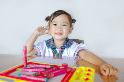 Smiling girl with crayons on table