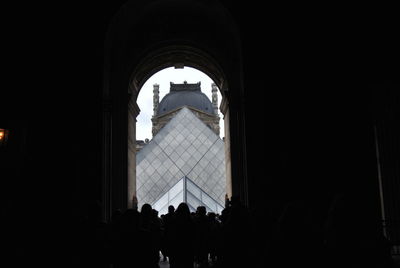 Silhouette people in temple seen through building