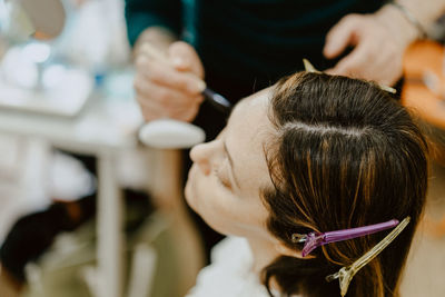 Midsection of man applying make-up for woman 