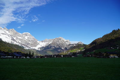 Scenic view of field and mountains against blue sky