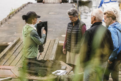 Female instructor explaining senior men and woman about life jacket during boat master course