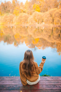 Rear view of woman sitting by lake