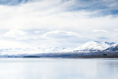 Idyllic shot of lake and snowcapped mountains against cloudy sky