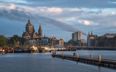 River passing through city against cloudy sky