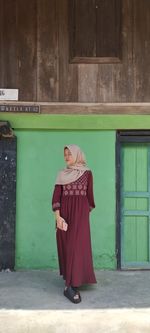 Young woman standing against wall