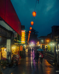 People walking on illuminated street at night