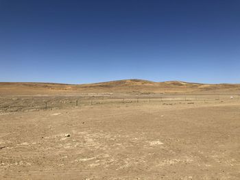 Scenic view of desert against clear blue sky