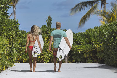 Couple with surfboards walking to the beach