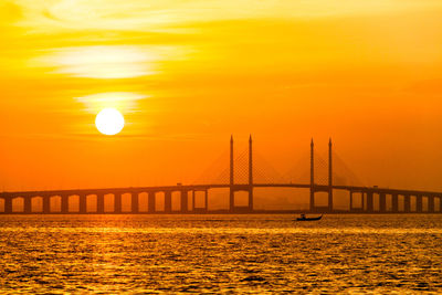 View of suspension bridge over sea during sunset