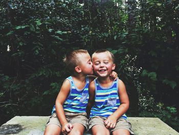 Happy friends sitting against plants