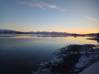 Scenic view of lake against sky at sunset