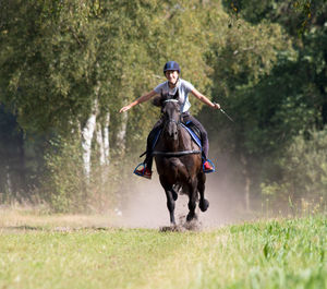 Young woman riding horse on grassy field