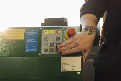 Cropped image of female mechanic using machine in auto repair shop