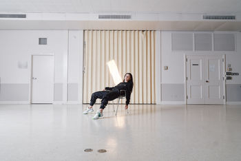 SIDE VIEW OF A YOUNG MAN WITH ARMS RAISED ON FLOOR