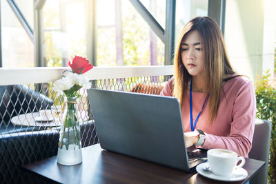 Young woman using laptop on table at home