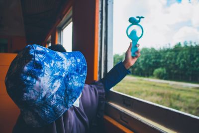 Close-up of woman holding toy at window of train