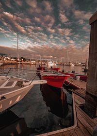 Boats moored at harbor during sunset