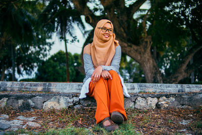 Portrait of smiling young woman against trees