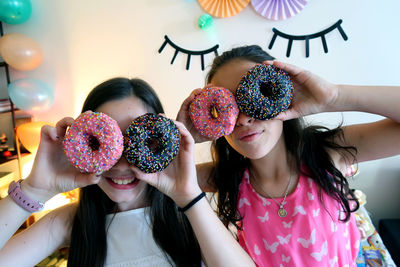 Playful girls with donuts during party at home