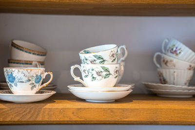 Hand painted ceramic floral pattern teacups with saucers on shelves