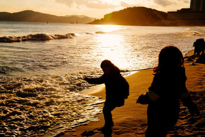 Silhouette people on beach during sunset