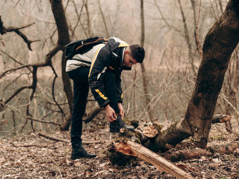 Man standing by bare trees in forest