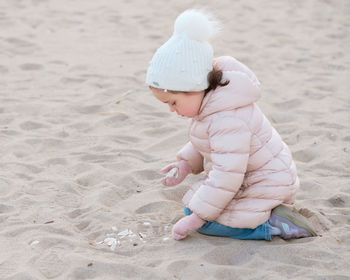 Little girl is playing on an empty beach on a cold day