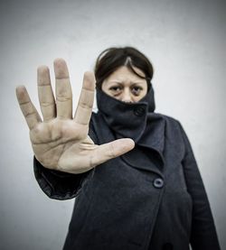 Portrait of mid adult woman showing stop gesture against wall