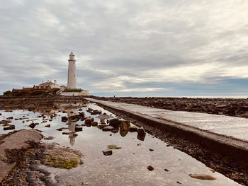 Lighthouse by sea against sky