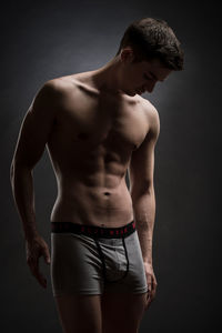 Midsection of shirtless man against black background