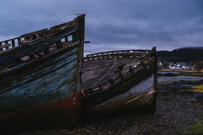 Abandoned boat on beach against sky