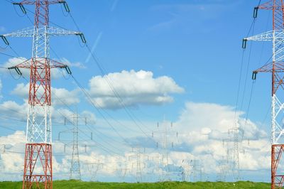 Electricity pylons on landscape against blue sky