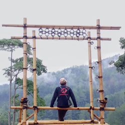 Rear view of man standing by railing against sky