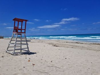 Lifeguard hut on beach against blue sky