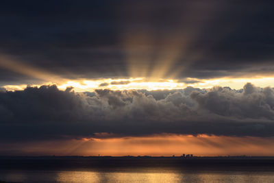 Scenic view of sea against dramatic sky during sunset