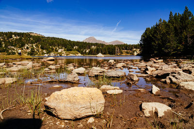 Rocks by lake against sky