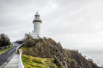 Lighthouse amidst sea and buildings against sky