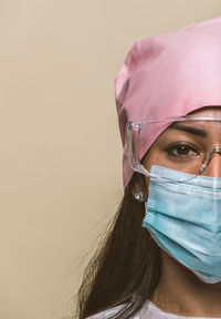 Close-up portrait of doctor wearing mask against colored background