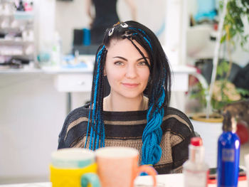 Portrait of young woman with dyed dreadlocks sitting in salon