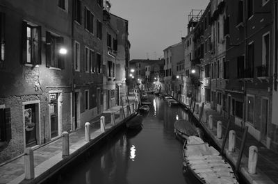 Canal amidst illuminated city at night