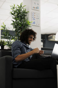 Side view of man using laptop while sitting on sofa at home