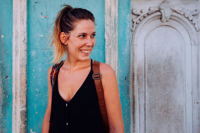 Portrait of smiling woman standing against door