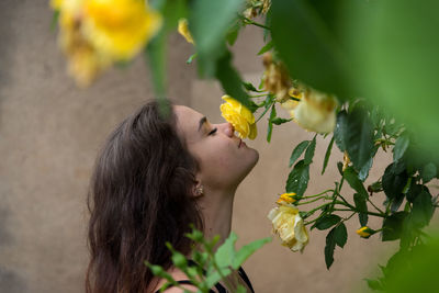 Side view of woman smelling yellow flower