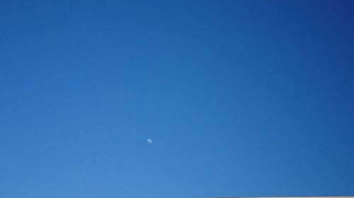 Low angle view of moon against clear blue sky