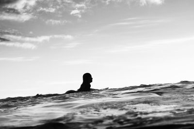 Silhouette woman swimming in sea against sky