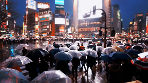 Rear view of people with umbrella walking on street in city