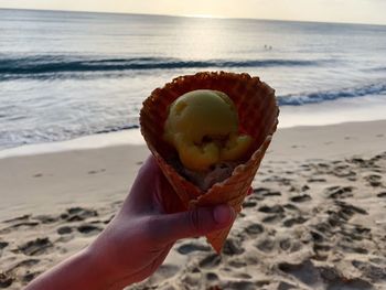 Close-up of hand holding ice cream on beach