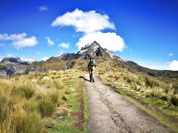 Man walking on mountain road against sky