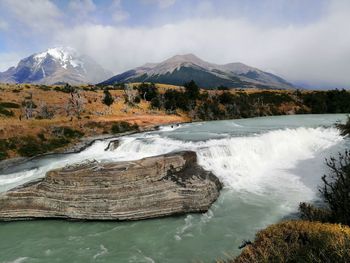 Scenic view of waterfall and mountains against sky