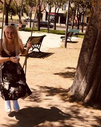 Cheerful woman on swing at park